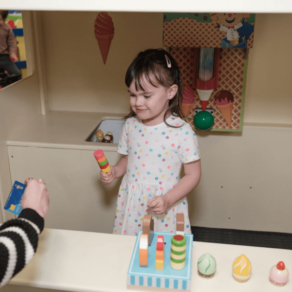 A little girl playing with the pretend ice cream set in the role-play area at Jack in the Box Club, enjoying a fun ice cream-making experience.